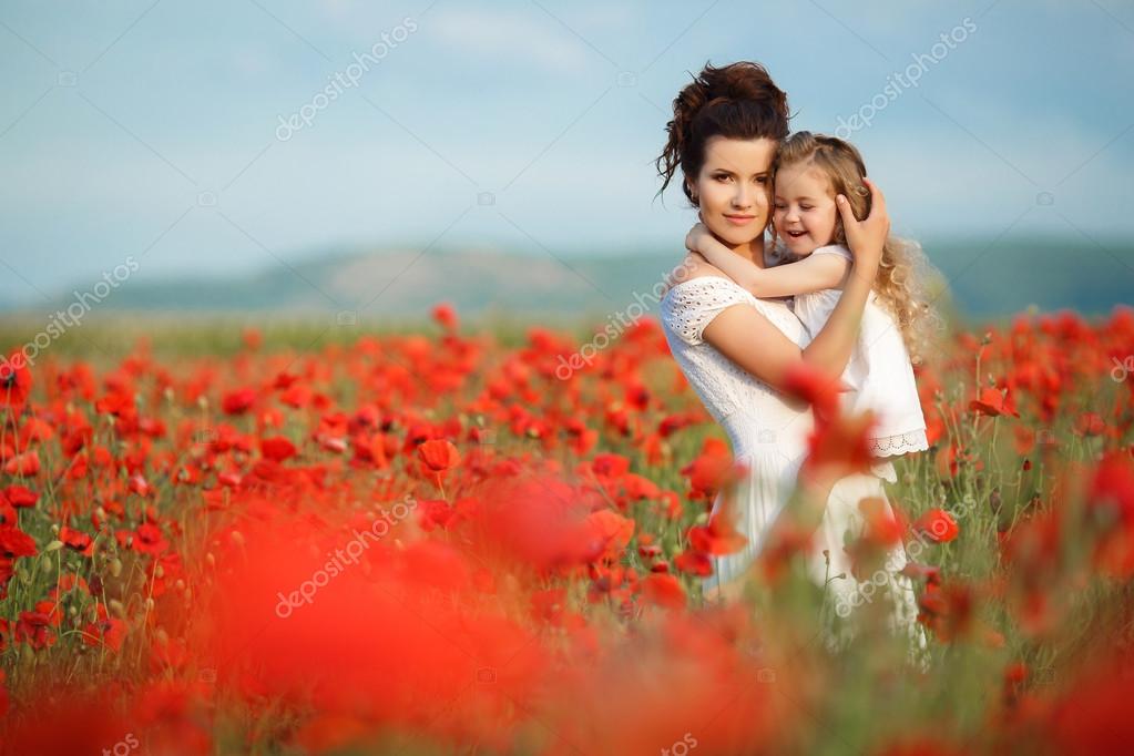 Mère avec sa petite fille dans les bras dans un champ de coquelicots en