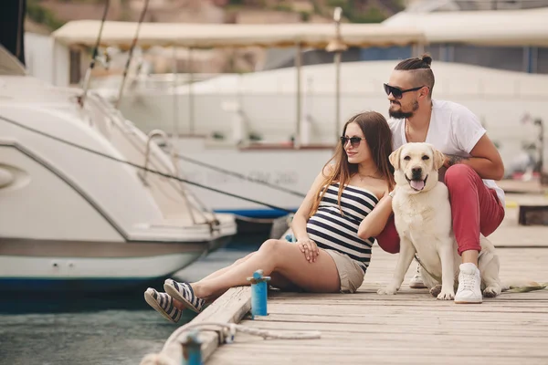 Jovem casal em um passeio no porto com um Labrador branco — Fotografia de Stock
