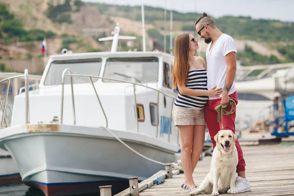 Jovem casal em um passeio no porto com um Labrador branco — Fotografia de Stock