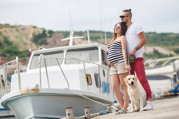 Pareja joven en un paseo por el puerto con un Labrador blanco —  Fotos de Stock