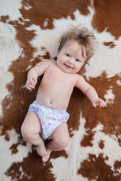 Cute baby with beautiful blue eyes smiling lying in bed — Stock Photo, Image