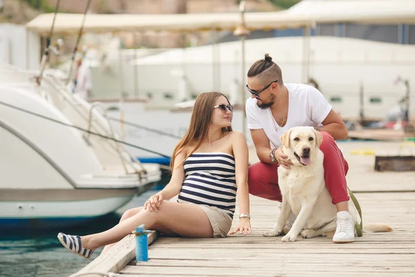 Jovem casal em um passeio no porto com um Labrador branco — Fotografia de Stock