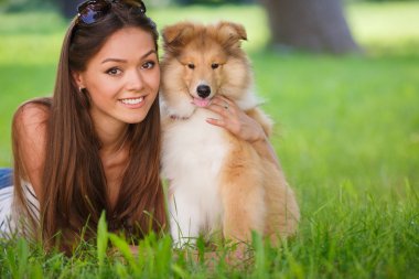 Bir küçük köpek yavrusu collie ile yeşil bir parkta oynayan genç güzel kadın