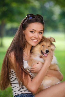 Bir küçük köpek yavrusu collie ile yeşil bir parkta oynayan genç güzel kadın