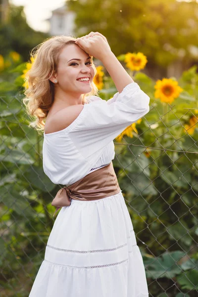 Junge hübsche Frau in einem Feld blühender Sonnenblumen — Stockfoto