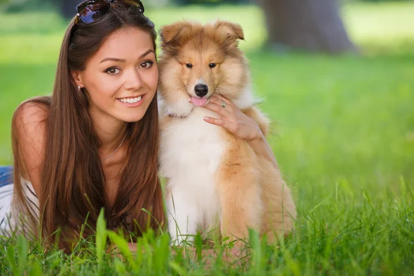 年轻美丽的女人在绿色公园里和一只小狗小马玩耍 — 图库照片