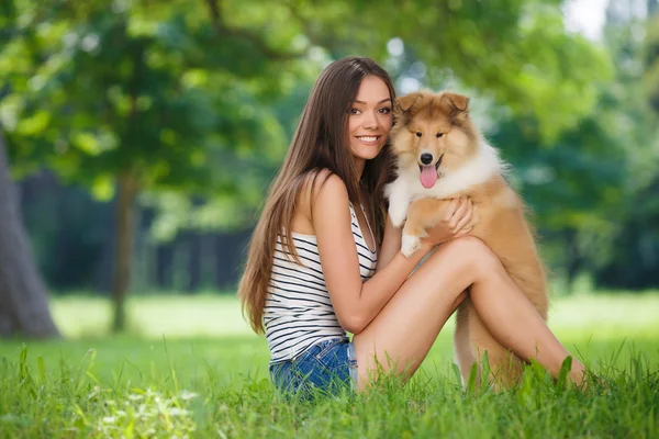 Bir küçük köpek yavrusu collie ile yeşil bir parkta oynayan genç güzel kadın