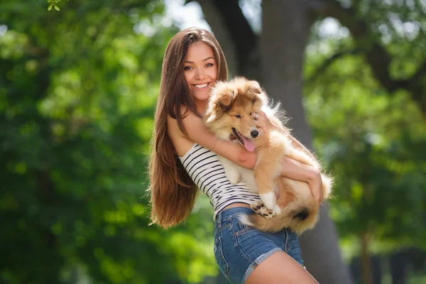 Bir küçük köpek yavrusu collie ile yeşil bir parkta oynayan genç güzel kadın — Stok fotoğraf