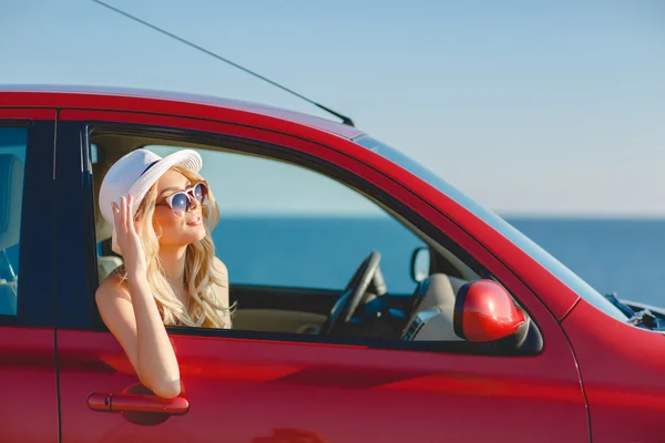 Belle blonde voyageant en voiture rouge . — Photo