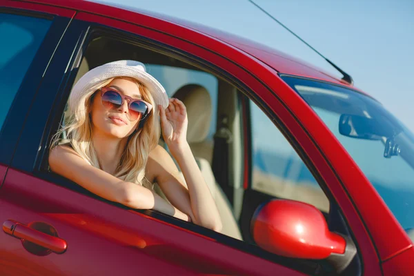 Beautiful blonde traveling in a red car. — Stock Photo, Image