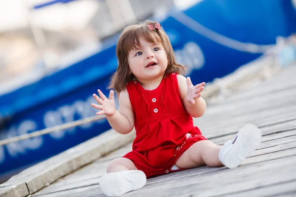 Kleines Mädchen sitzt auf einem hölzernen Steg — Stockfoto