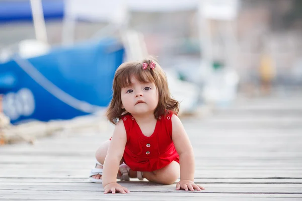 Liten flicka sitter på en träbrygga — Stockfoto