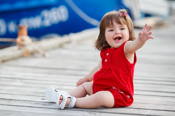 Ahşap bir iskele üzerinde oturan küçük kız — Stok fotoğraf
