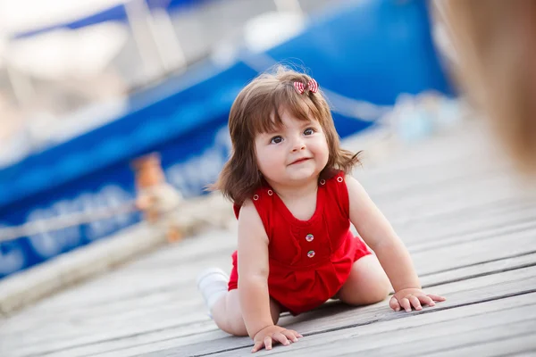 Liten flicka sitter på en träbrygga — Stockfoto