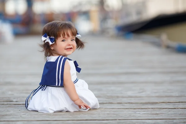 Ahşap bir iskele üzerinde oturan küçük kız — Stok fotoğraf