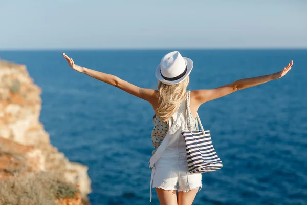 La chica mira al mar, de pie sobre una roca — Foto de Stock