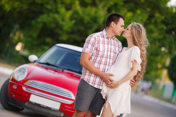 Het gelukkige paar liefdevolle reist in de rode auto — Stockfoto