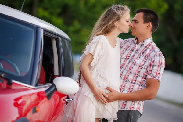 O casal amoroso feliz viaja no carro vermelho — Fotografia de Stock