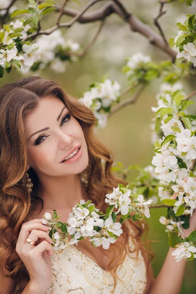 Young beautiful brunette woman in blooming garden — Stock Photo, Image