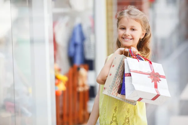 Ragazzina sorridente con borse della spesa in un grande supermercato . — Foto Stock