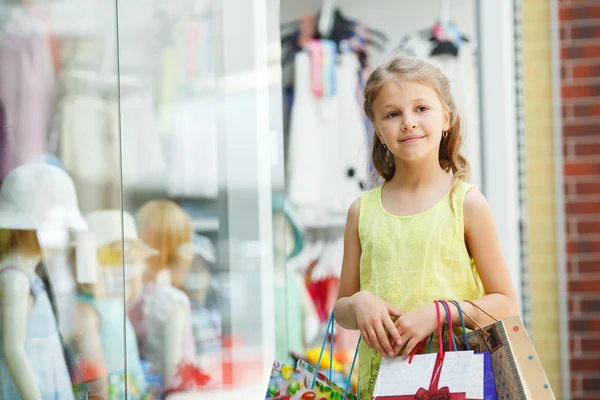 Улыбающаяся маленькая девочка с сумками в большом супермаркете . — стоковое фото