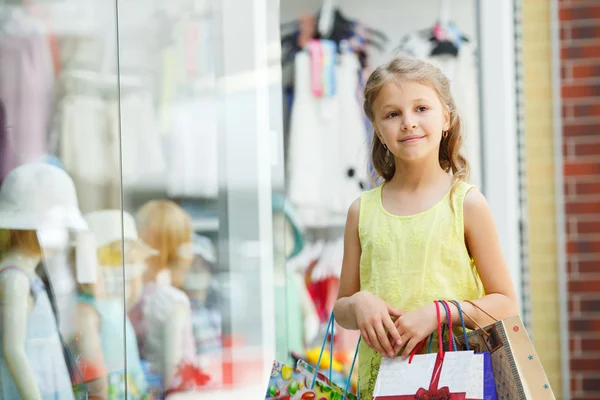 Smiling little girl with shopping bags in a large supermarket. — 图库照片