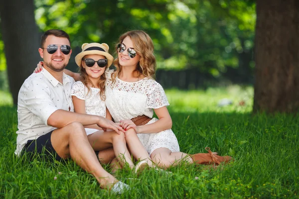 Mutlu genç aile dışarıda yeşil doğada birlikte vakit geçiriyor. — Stok fotoğraf