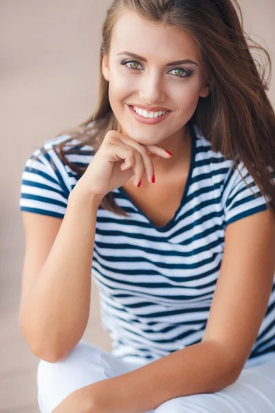 Cheerful beautiful woman smiling sitting on the road — Stock Photo, Image