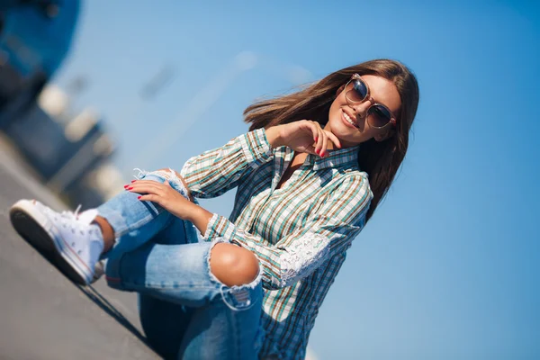 Cheerful beautiful woman smiling sitting on the road — Stock fotografie