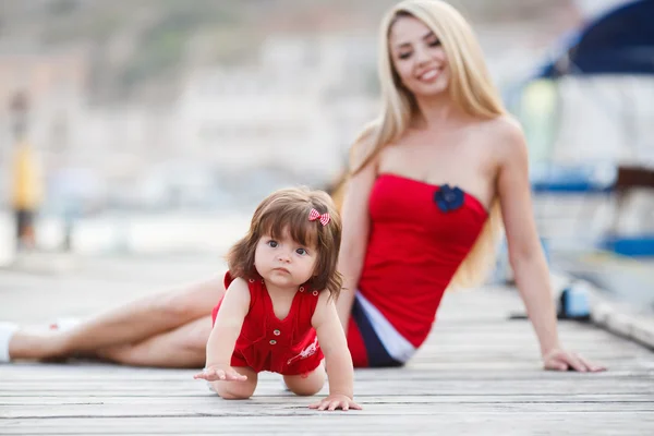 Glückliche junge Mutter mit kleiner Tochter in der Nähe des Yachtclubs — Stockfoto