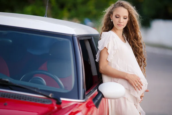 Menina morena grávida e seu carro vermelho — Fotografia de Stock