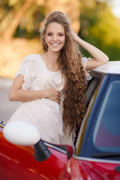 Pregnant brunette girl and her red car — Stock Photo, Image