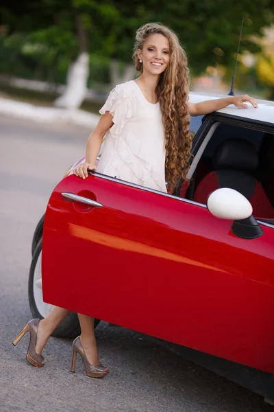 Chica morena embarazada y su coche rojo — Foto de Stock