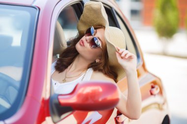 Happy woman driving a red compact car