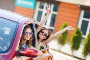 Two happy girlfriends are traveling in the car