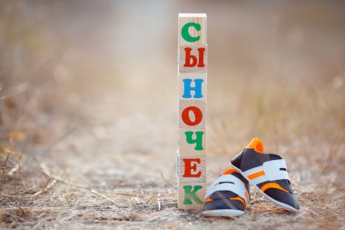 Children's shoes and the word son, paved with wooden cubes