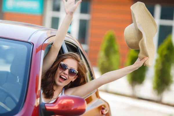 Счастливая женщина за рулем красной компактной машины — стоковое фото