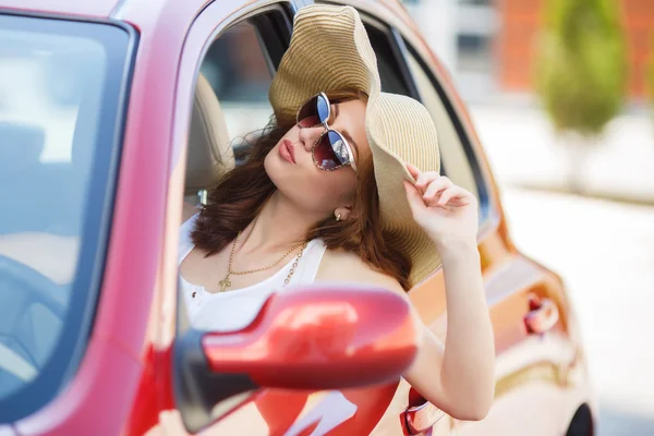 Happy woman driving a red compact car — 스톡 사진