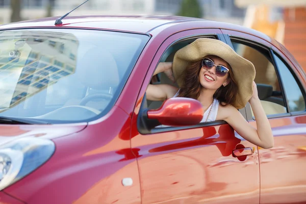 Happy woman driving a red compact car — 스톡 사진