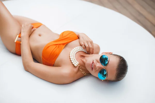 Mulher bonita em um sofá branco perto da piscina — Fotografia de Stock