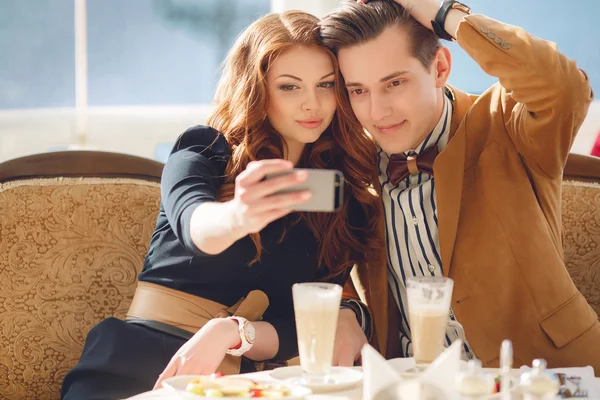 Casal jovem assistindo fotos no celular, sentado em um caf — Fotografia de Stock