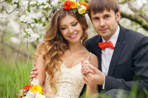 Ritratto sposi novelli nel lussureggiante giardino primaverile — Foto Stock