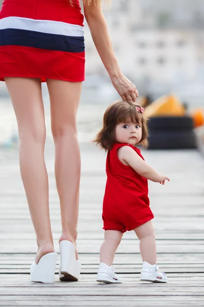 Mère et petite fille marchant le long du front de mer — Photo