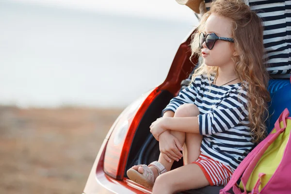 Porträt eines kleinen Mädchens, das im Kofferraum eines Autos sitzt — Stockfoto