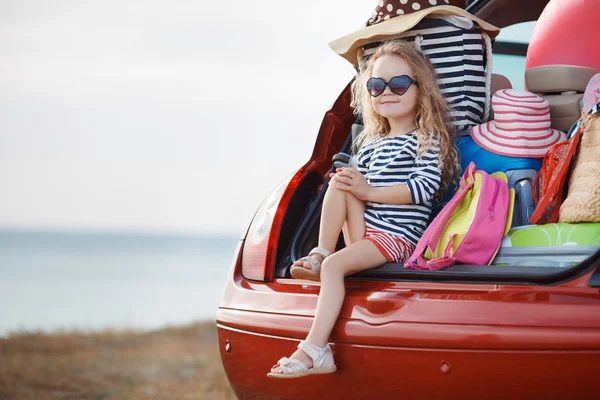 Portrait of a little girl sitting in the trunk of a car — Stock Photo, Image