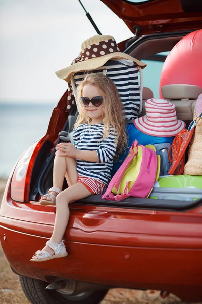 Porträt eines kleinen Mädchens, das im Kofferraum eines Autos sitzt — Stockfoto