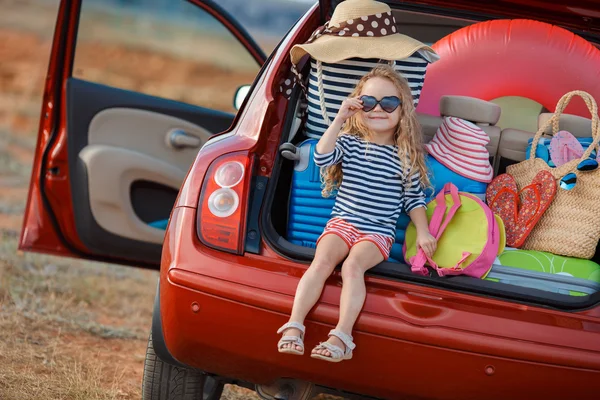 Bir arabanın bagajında oturan küçük bir kız portresi