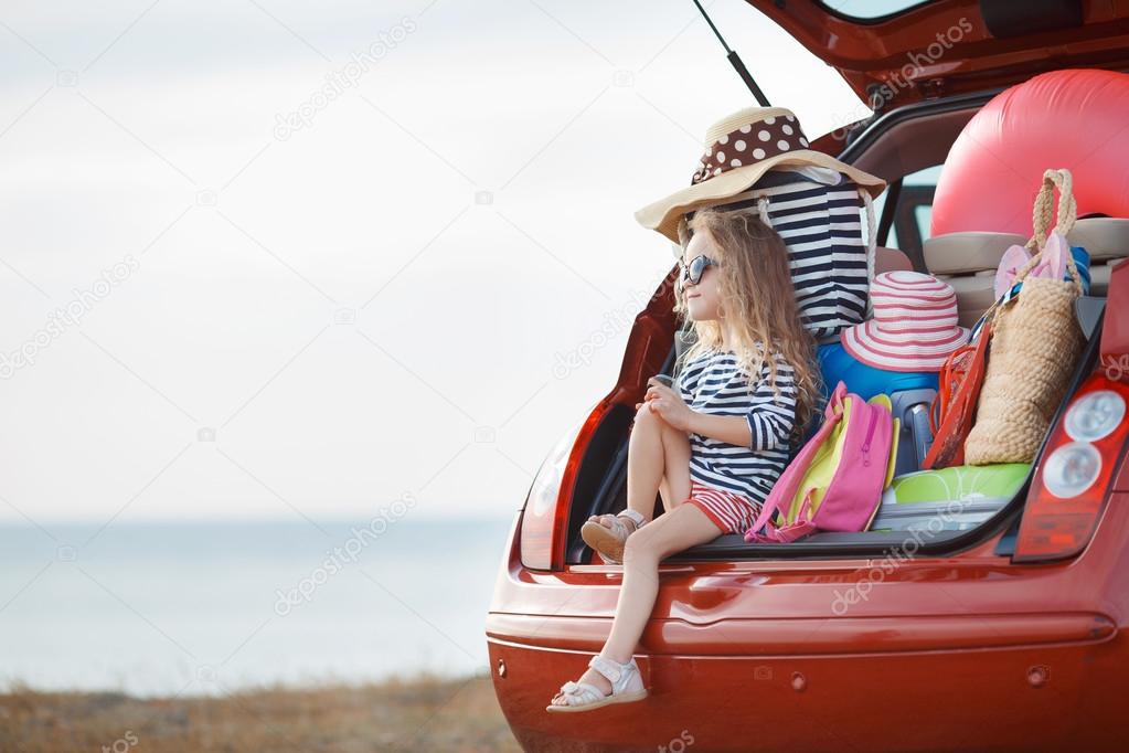 Portrait of a little girl sitting in the trunk of a car