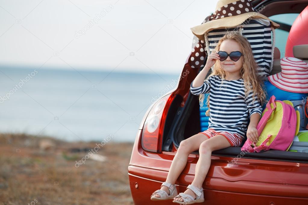 Portrait of a little girl sitting in the trunk of a car