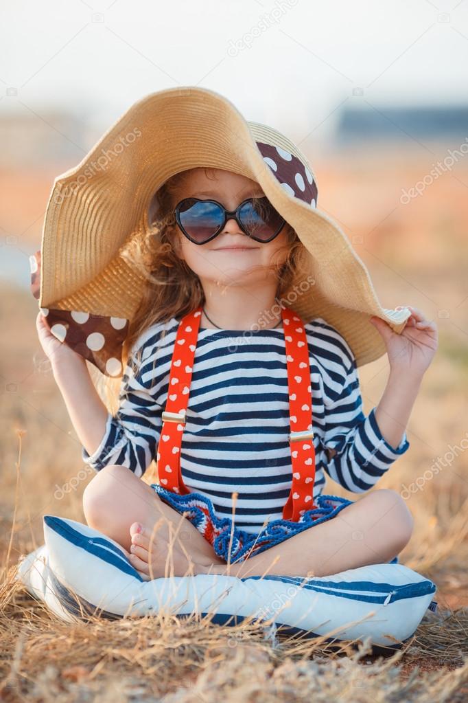 The happy little girl in a big hat